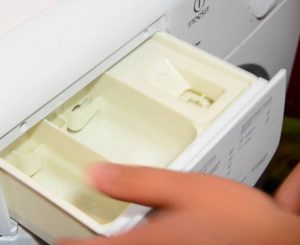 How to clean the detergent container in an Indesit washing machine?