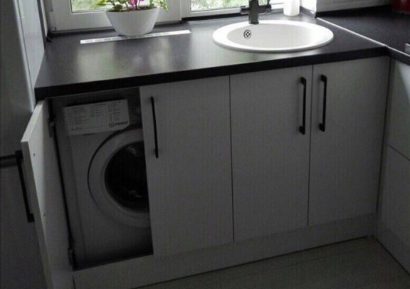 a washing machine under the windowsill in the kitchen