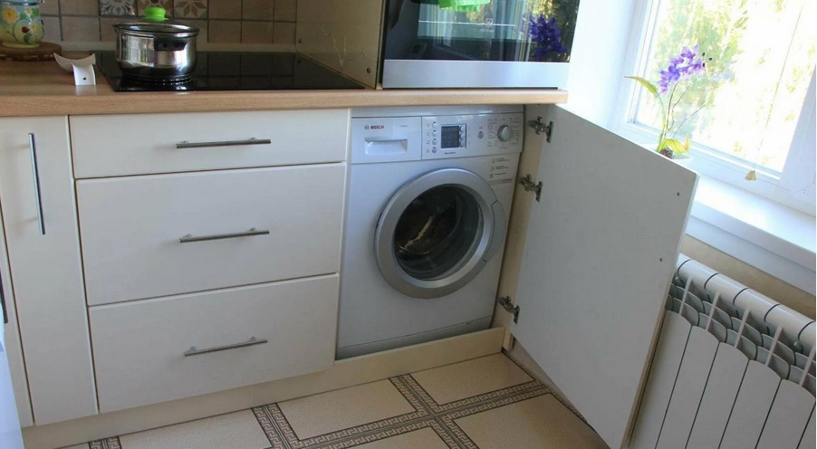 a washing machine in the kitchen by the window