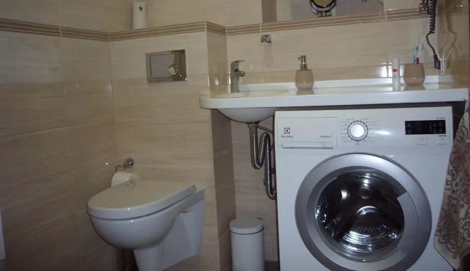 the machine is next to the toilet under the sink